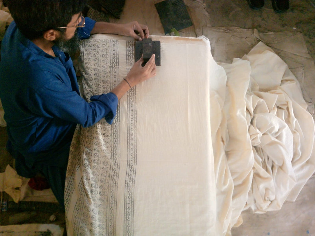 Artisan creating hand block printed fabric using traditional wooden blocks and natural dyes.