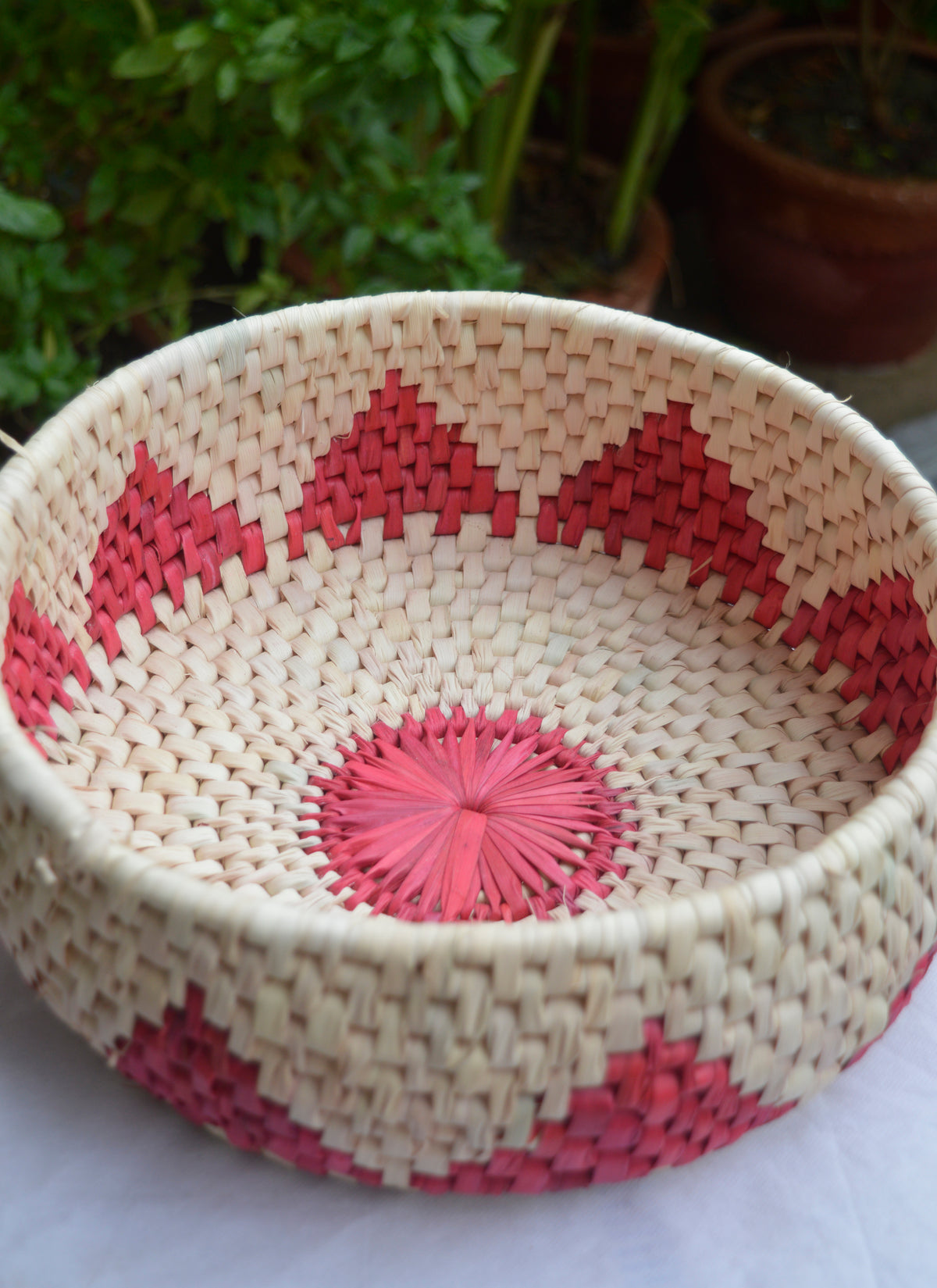 Handmade red palm leaf basket for roti, bread, or fruits, sustainable kitchen accessory.