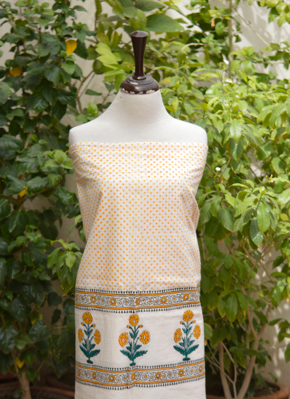 Traditional hand block printed cotton fabric with golden yellow dots and floral border detailing