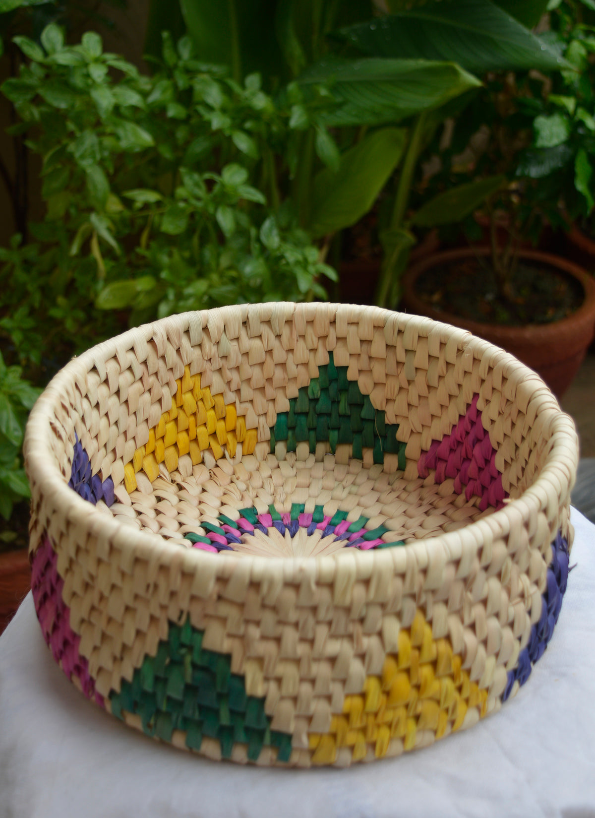 Eco-friendly handwoven roti dan with lotus flower motif, multi-color datepalm leaf basket for serving bread, roti, or fruits, sustainable Sindhi craft.