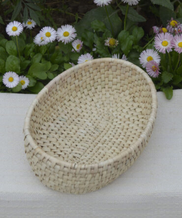 A beautifully crafted oval basket made from sustainable palm leaves, showcasing its natural color and firm structure.