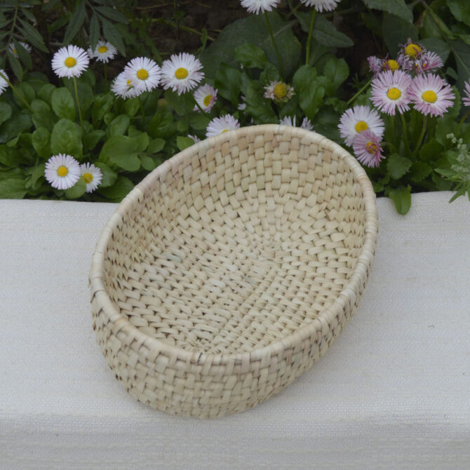 A beautifully crafted oval basket made from sustainable palm leaves, showcasing its natural color and firm structure.