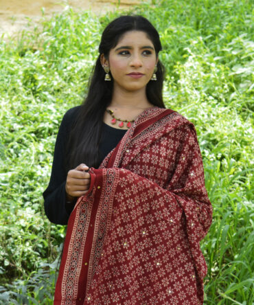 Organic Dye Hand Block Printed Ajrak Odhni Floral draped elegantly, showcasing intricate geometric and floral designs in mehroonish red with shimmering sitara sequences.