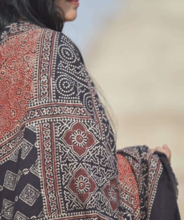 Close-up view of the detailed hand block printing on the Organic Dye Ajrak Odhni, showcasing vibrant red and black designs against a soft cotton fabric.