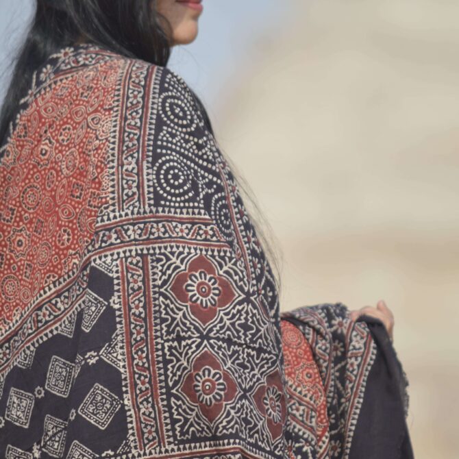 Close-up view of the detailed hand block printing on the Organic Dye Ajrak Odhni, showcasing vibrant red and black designs against a soft cotton fabric.