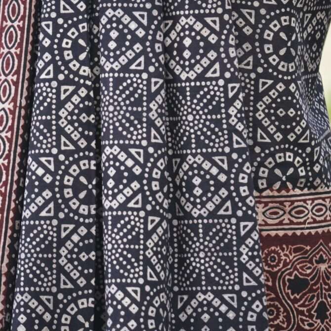 Close-up view of the un-stitched shirt featuring intricate hand block printed patterns in deep black and maroon, showcasing traditional Ajrak craftsmanship.