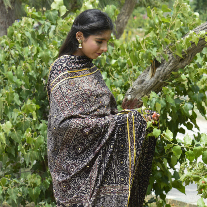 A beautiful Organic Dye Hand Block Printed Ajrak Chaadar Multi Blocks draped elegantly over a model, showcasing intricate floral and geometric designs in deep black.