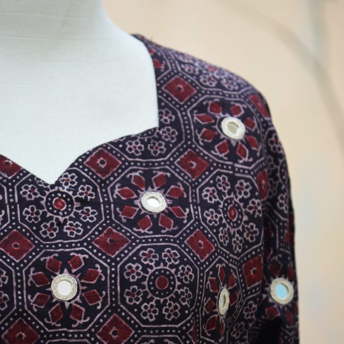 A detailed shot showcasing the hand block printed geometric and floral designs in black and maroon, with mirror embroidery work highlighting the kurta's craftsmanship.