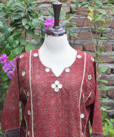 Close-up view of the intricate geometric and floral hand block-printed patterns on the deep red and black Ajrak Kurti, showcasing traditional craftsmanship.