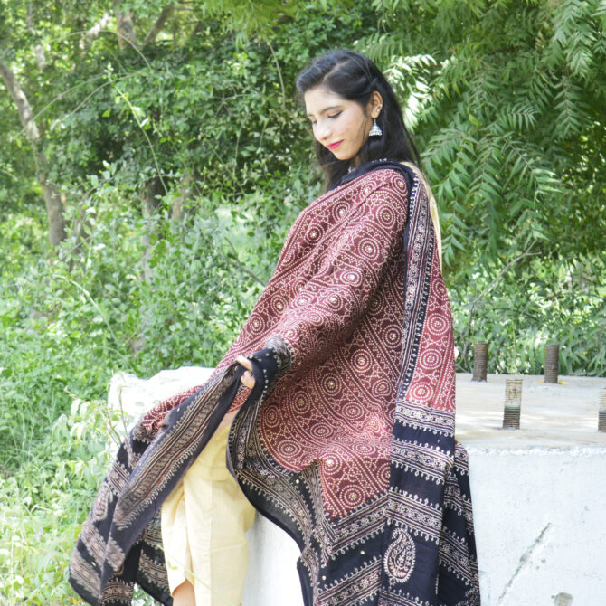 A stunning Organic Dye Hand Block Printed Ajrak Chunri Odhni with intricate red geometric and chunri patterns. The fabric is soft, breathable lawn cotton, measuring 2.5 meters long and 44 inches wide. Its traditional hand-printed design, crafted using eco-friendly dyes, makes it an elegant and sustainable fashion choice.