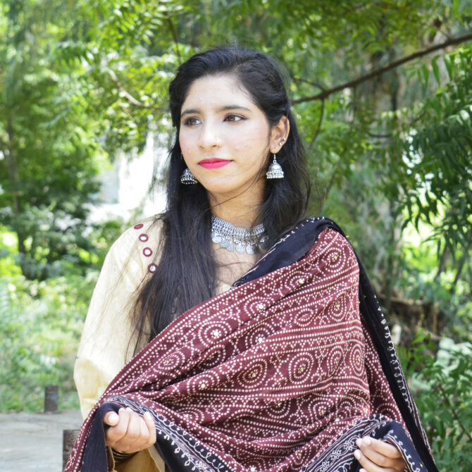 An eco-friendly, handcrafted Ajrak Chunri Odhni showcasing intricate red and black patterns. The 2.5-meter length and 44-inch width allow for versatile wear, while the breathable lawn cotton fabric provides comfort and elegance. Natural dyes and traditional block printing enhance its authenticity.