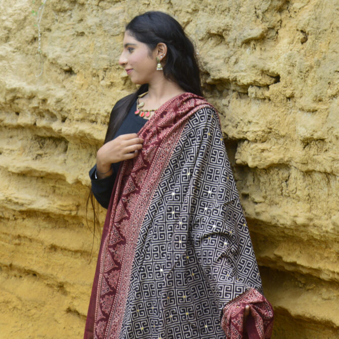 The Organic Dye Hand Block Printed Ajrak Odhni Taskeen styled as a dupatta, featuring its elegant design and vibrant colors that add a chic touch to a traditional outfit.