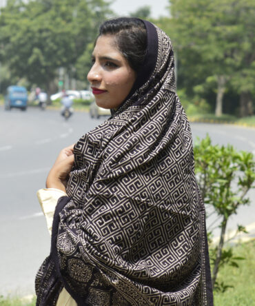 Organic Dye Hand Block Printed Ajrak Taskeen Odhni in Black, showcasing intricate geometric and floral patterns, draped elegantly over a model.