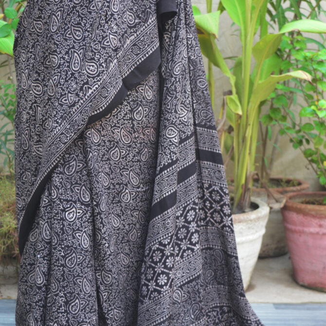 Black Ajrak Saree Anbi Floral draped elegantly, with organic, eco-friendly dyes and unique hand-printed patterns, offering both elegance and sustainability in traditional fashion.