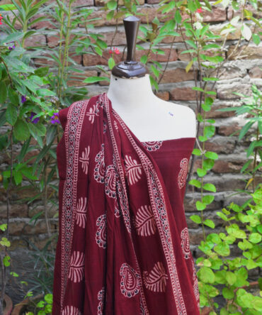 Close-up of Ajrak Red Anbi fabric, highlighting detailed hand block printed geometric and floral designs in deep red and golden hues on soft Lawn cotton.