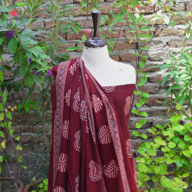 Close-up of Ajrak Red Anbi fabric, highlighting detailed hand block printed geometric and floral designs in deep red and golden hues on soft Lawn cotton.