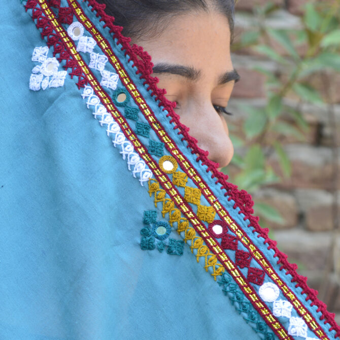 Woman wearing a hand embroidered Sindhi chaadar as a shawl, highlighting its colorful design and elegant draping.