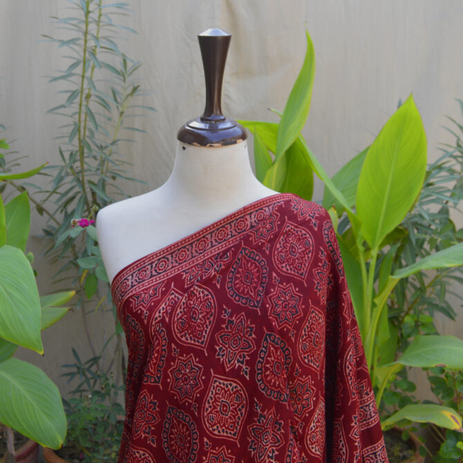 Close-up of the Ethnic Ajrak Saree in deep Reddish Maroon, highlighting traditional Ajrak hand block printing with eco-friendly organic dyes, showcasing detailed craftsmanship.