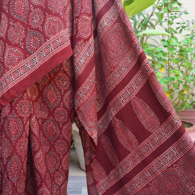 Detailed shot of the Ajrak Saree's intricate patterns in maroon and deep red, emphasizing the unique blend of traditional and contemporary design elements in sustainable Modal Silk.