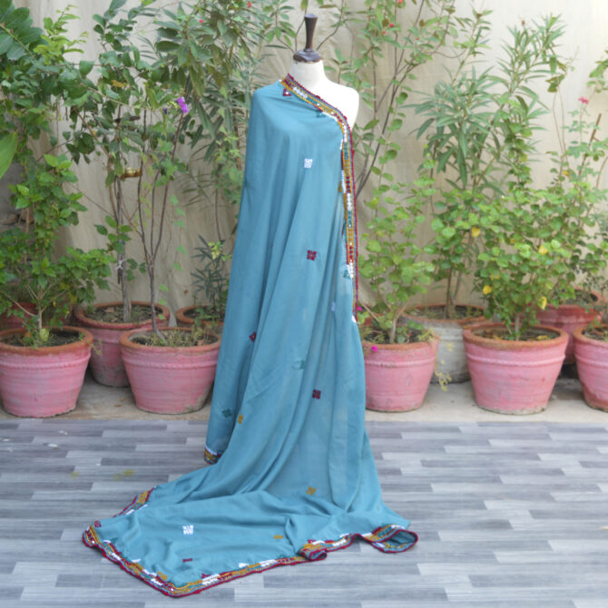 Hand embroidered Sindhi chaadar showcasing vibrant colors and intricate floral patterns, draped elegantly over a chair.