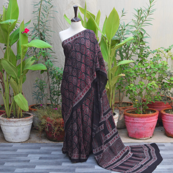 Ethnic Ajrak Saree Sundaree, a handcrafted saree featuring traditional Ajrak print, blending rich cultural heritage with contemporary style. The saree is elegantly draped, showcasing detailed artisan work and intricate patterns that reflect timeless craftsmanship.