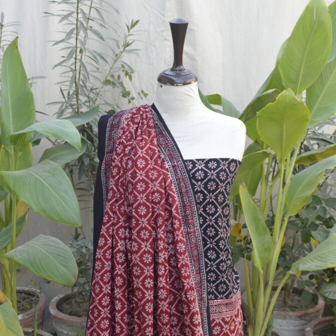 Organic Dye Hand Block Printed Ajrak Dress - Two-Piece Unstitched Set, featuring a floral and geometric design in black and red on luxurious Leelan fabric, displayed with a folded dupatta.